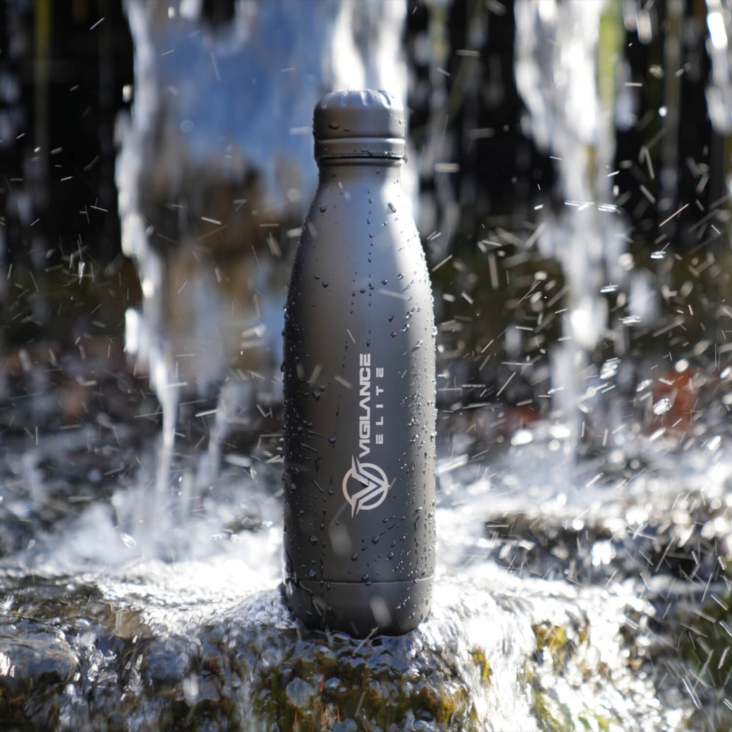 Black Vigilance Elite Beverage Bottle sitting in front of a water fall